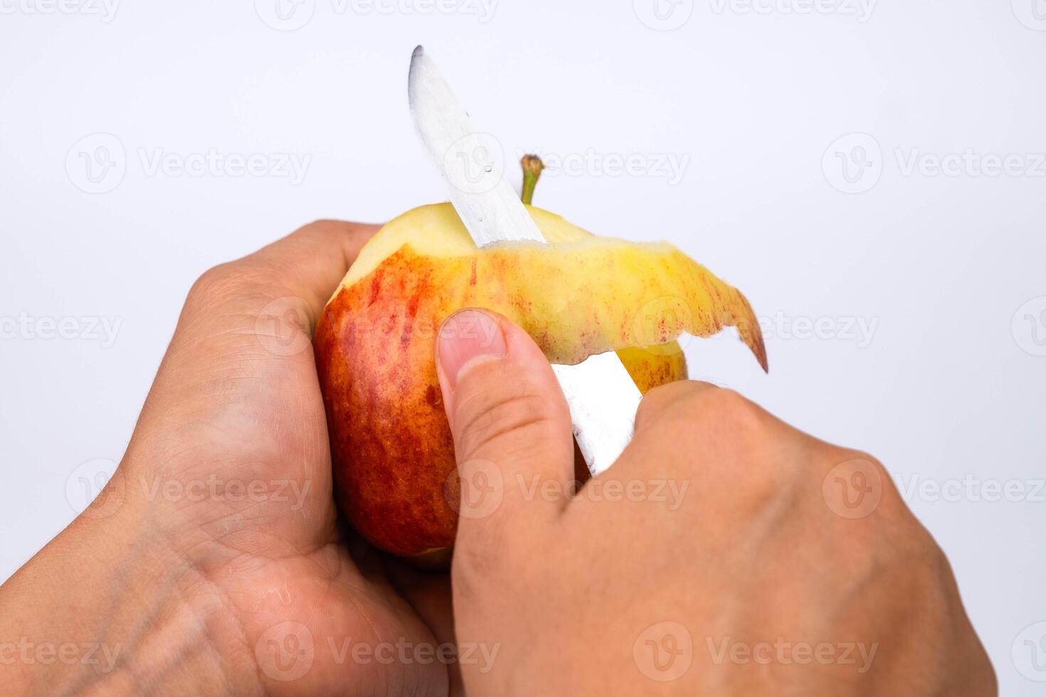 Hand peeling apple with knife close up. Woman peeling a red apple in the kitchen. photo