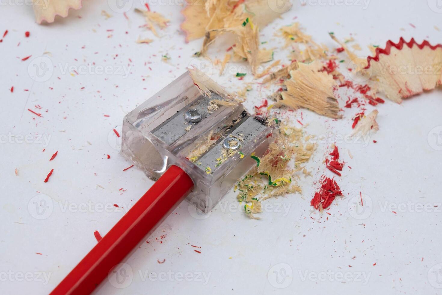 Colored pencils or pencils and sharpener isolated on white background. Red wooden pencil and pencil shavings on white table. photo