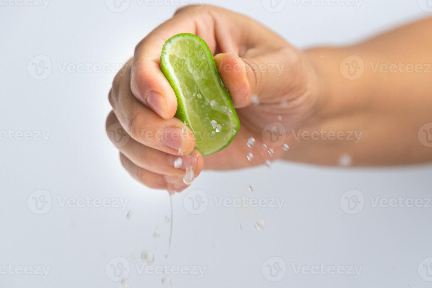 Female hand squeezing half fresh lemon isolated on white background. Squeezing fresh lemon close up. Hight Vitamin C Natural photo