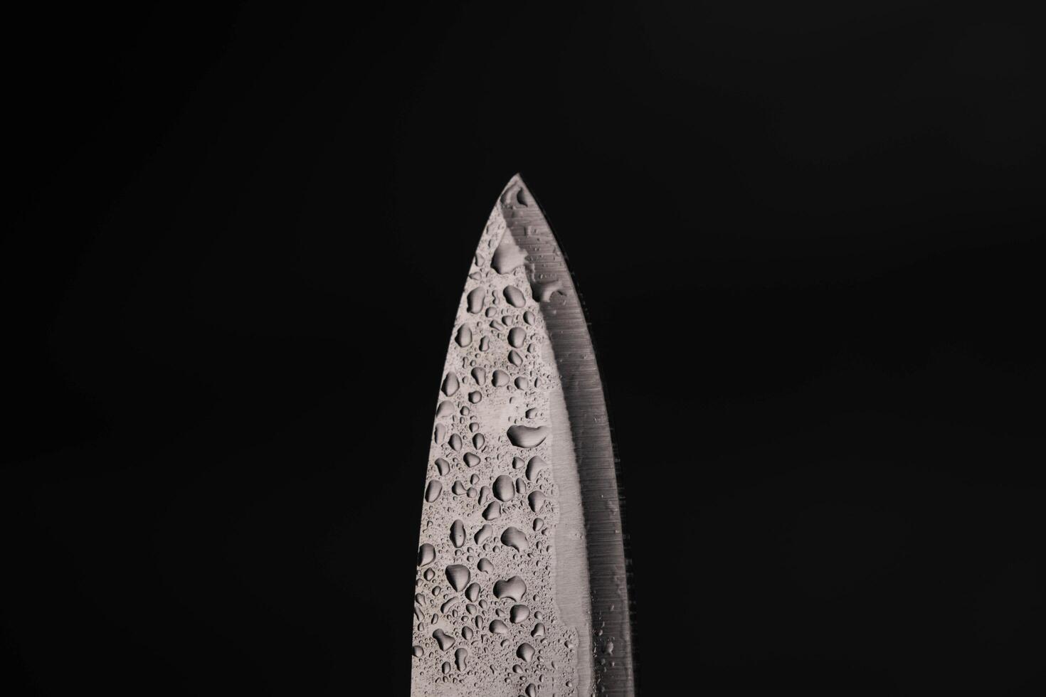 Water drop on sharp knife isolated on dark background. water splashing on knife. photo