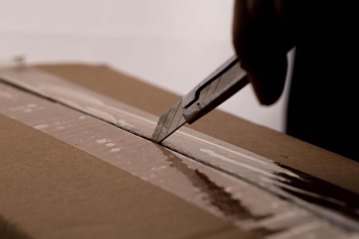 de cerca de mujer mano apertura caja utilizando cortador. manos desempacar cartulina cajas en el casa. foto