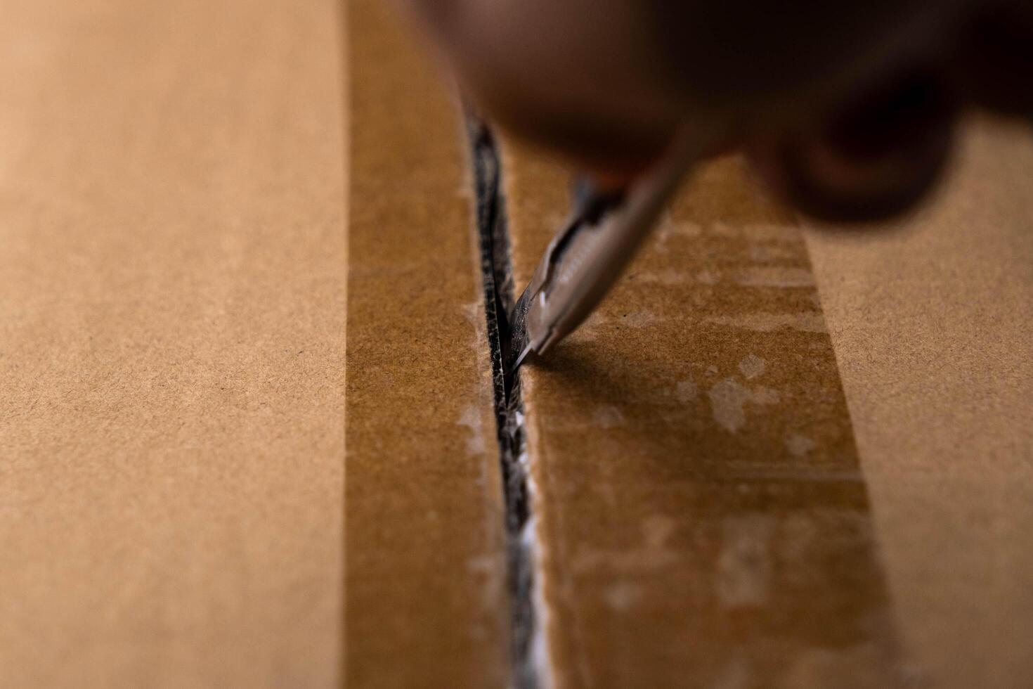 Close-up of woman's hand opening box using cutter. Hands unpacking cardboard boxes in the house. photo