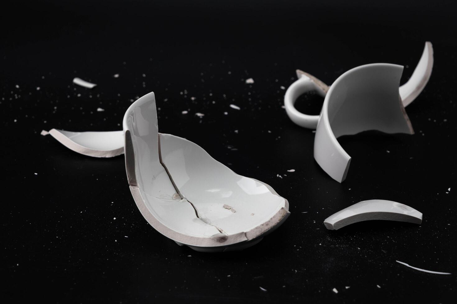 Large white mug with cracks. White cup for tea or soup with cracks isolated on dark background. Broken ceramic cup close up. symbol of divorce or loss photo