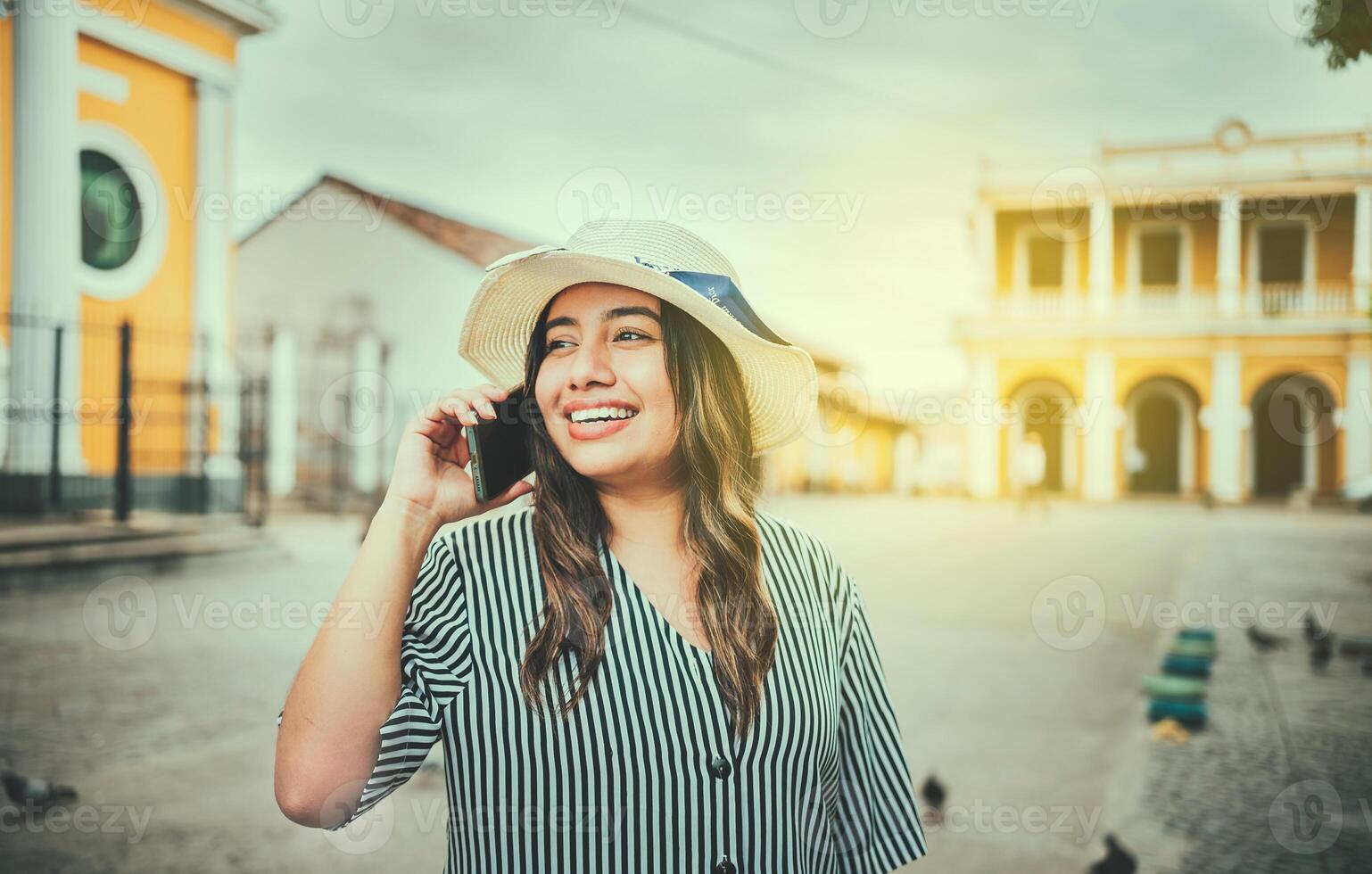 Beautiful tourist girl talking on cell phone in the square. Granada, Nicaragua. Happy travel woman calling on the phone in a tourist plaza photo