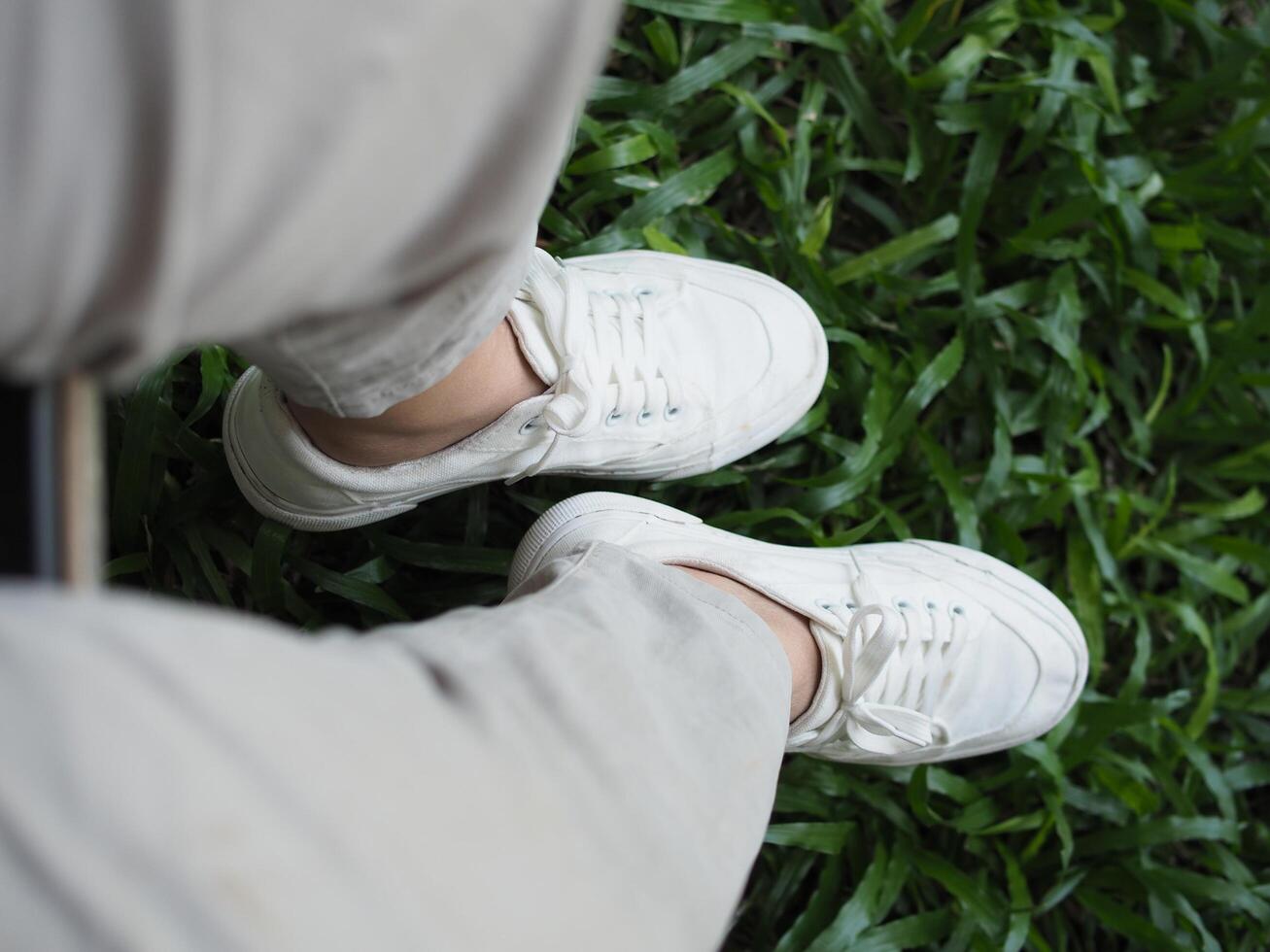 white canvas shoes on green and wooden backgrjound classic style easy and smooth life style photo