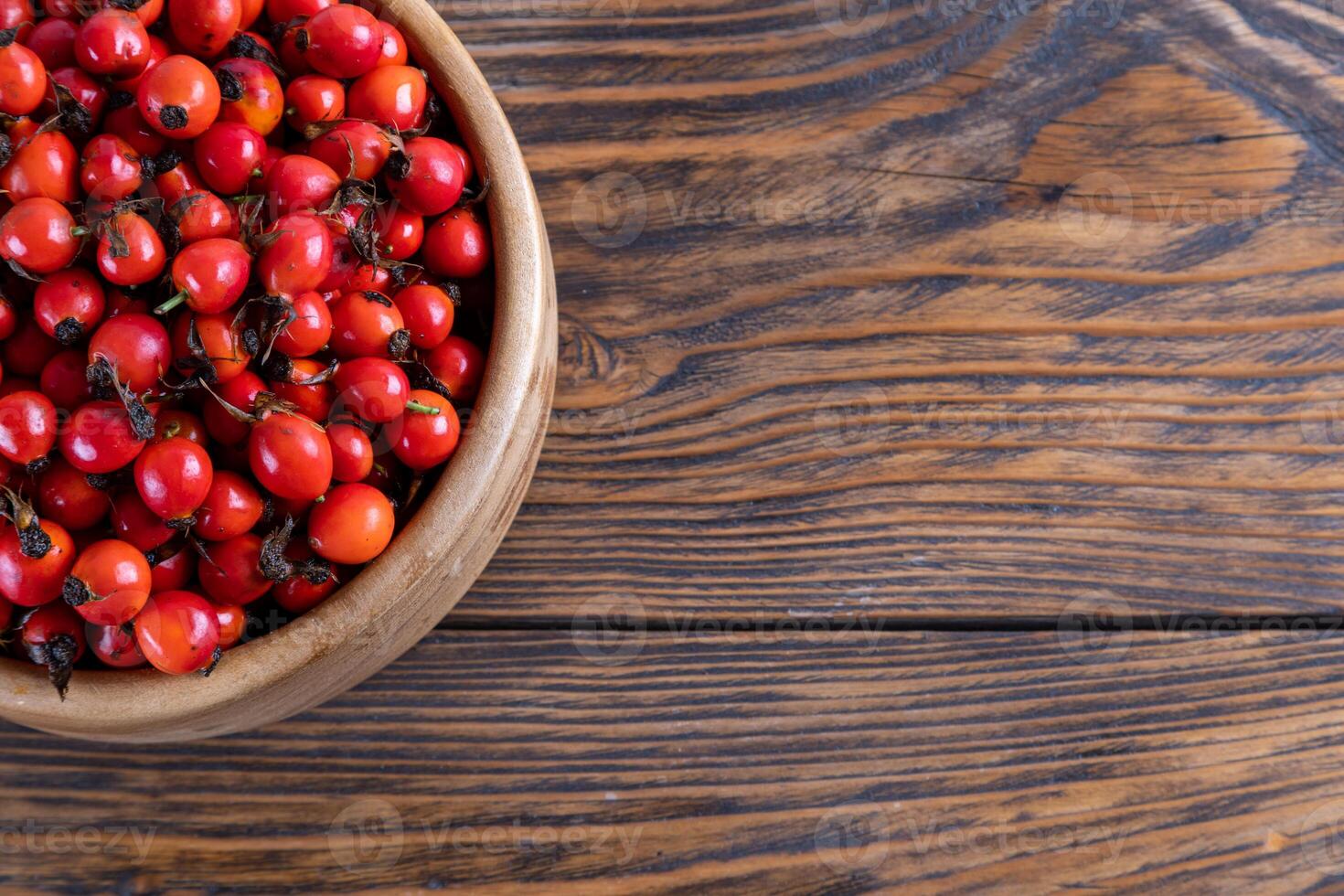 rojo perro se levantó rosa mosqueta frutas en un de madera cuenco en de madera mesa foto