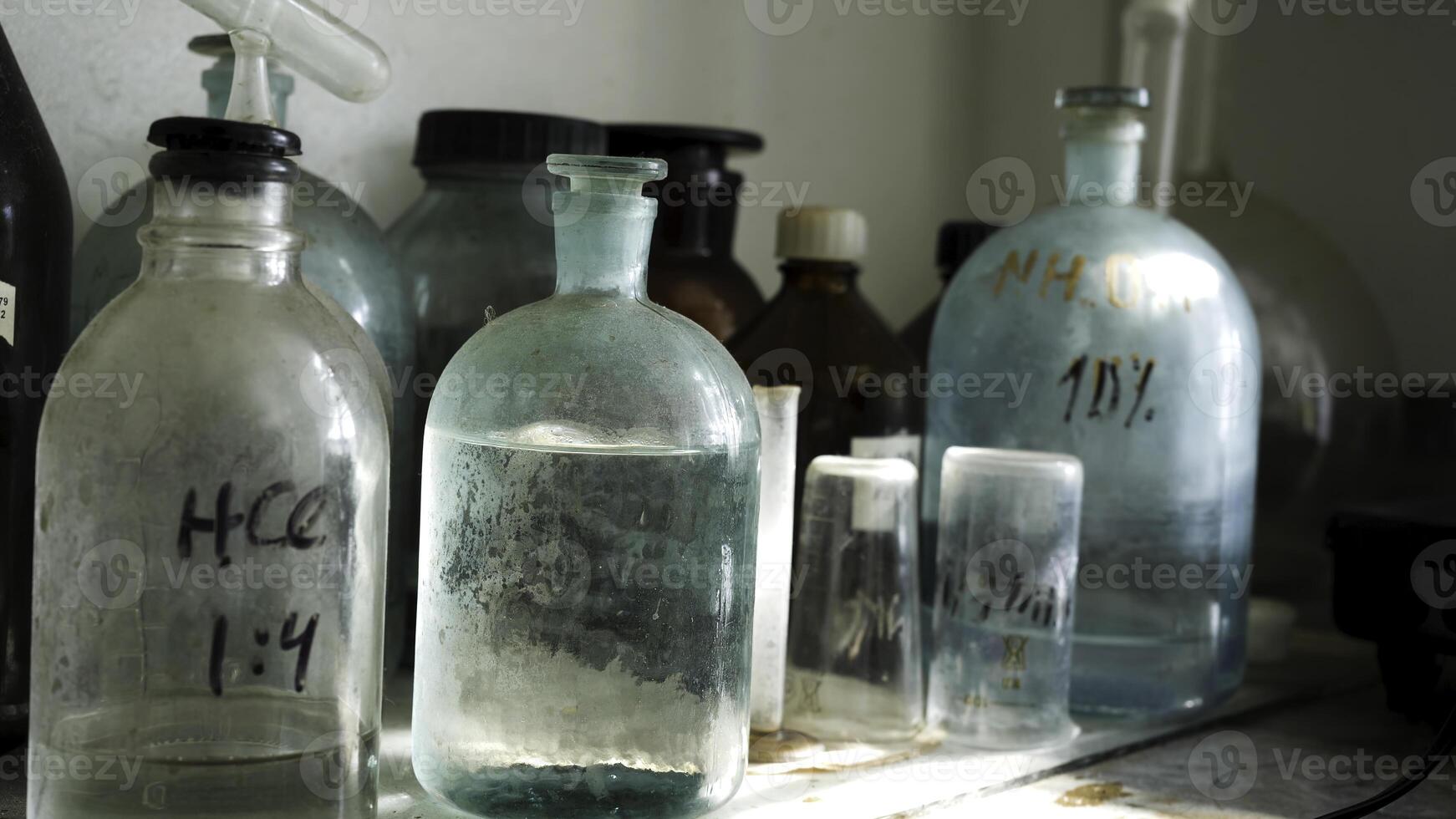 Chemistry laboratory with acid solutions in old glass flasks. Close up for the table with chemical solutions in the lab, science concept. photo