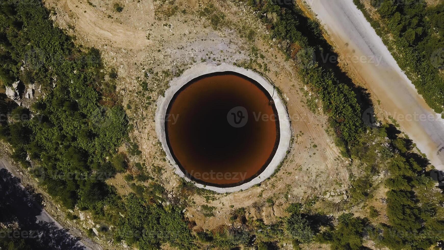 Top view of Sinkhole. Clip. Incredible natural phenomenon in form of sinkhole with brown water in field. Karst sinkhole with water near highway in field photo