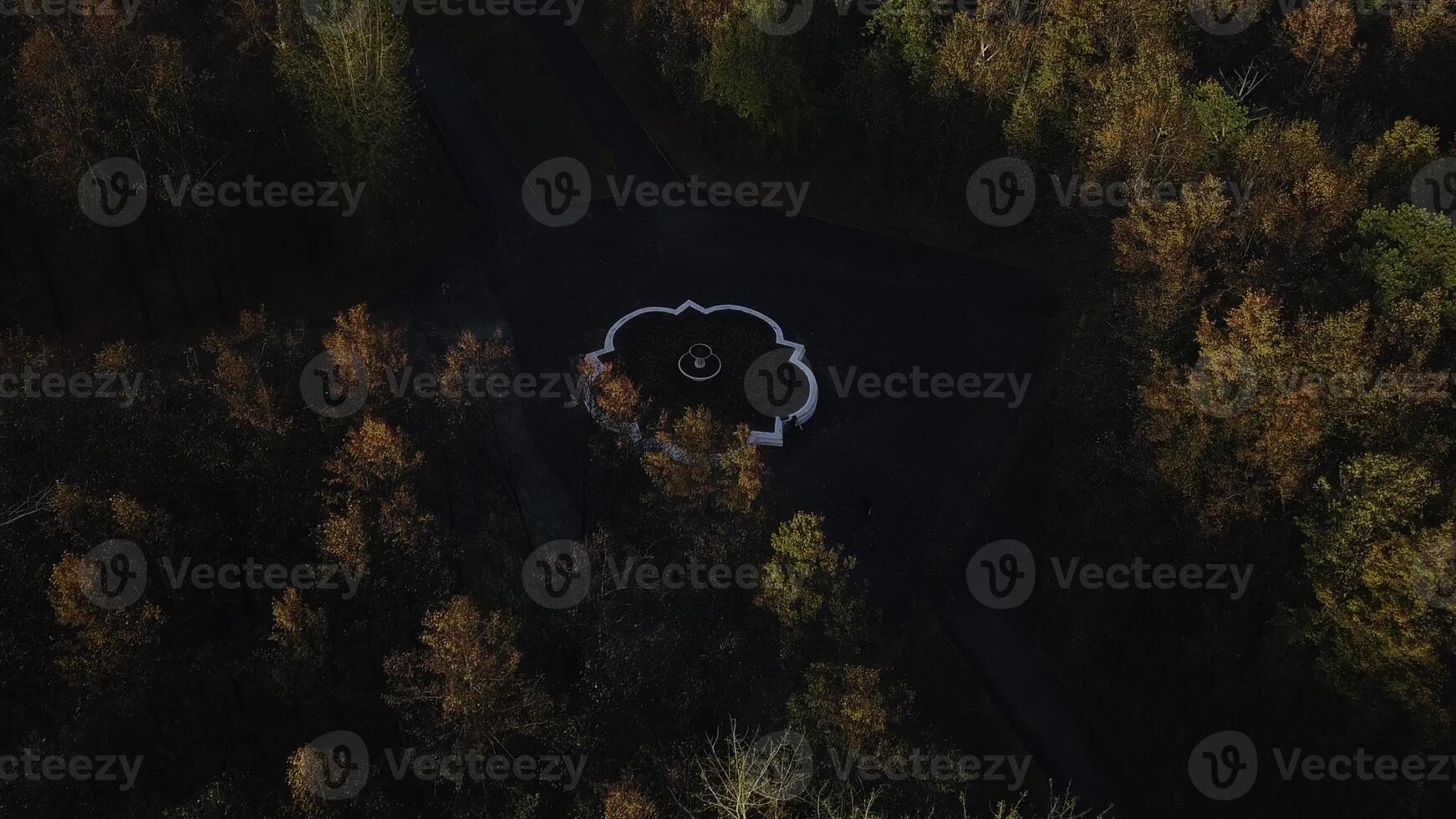 Top view of fountain and roads in autumn forest. Clip. Roads intersect in center with fountain. Crossroads with fountain in autumn forest on cloudy day photo