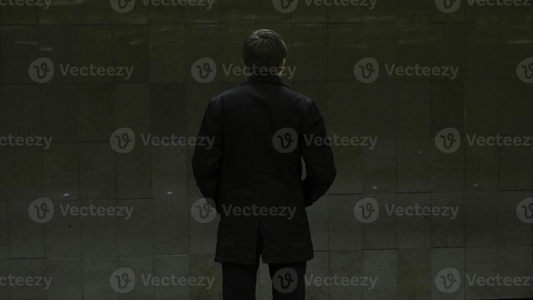 Lonely young man from behind at subway station. Young man waits for a train in the subway, rear view photo