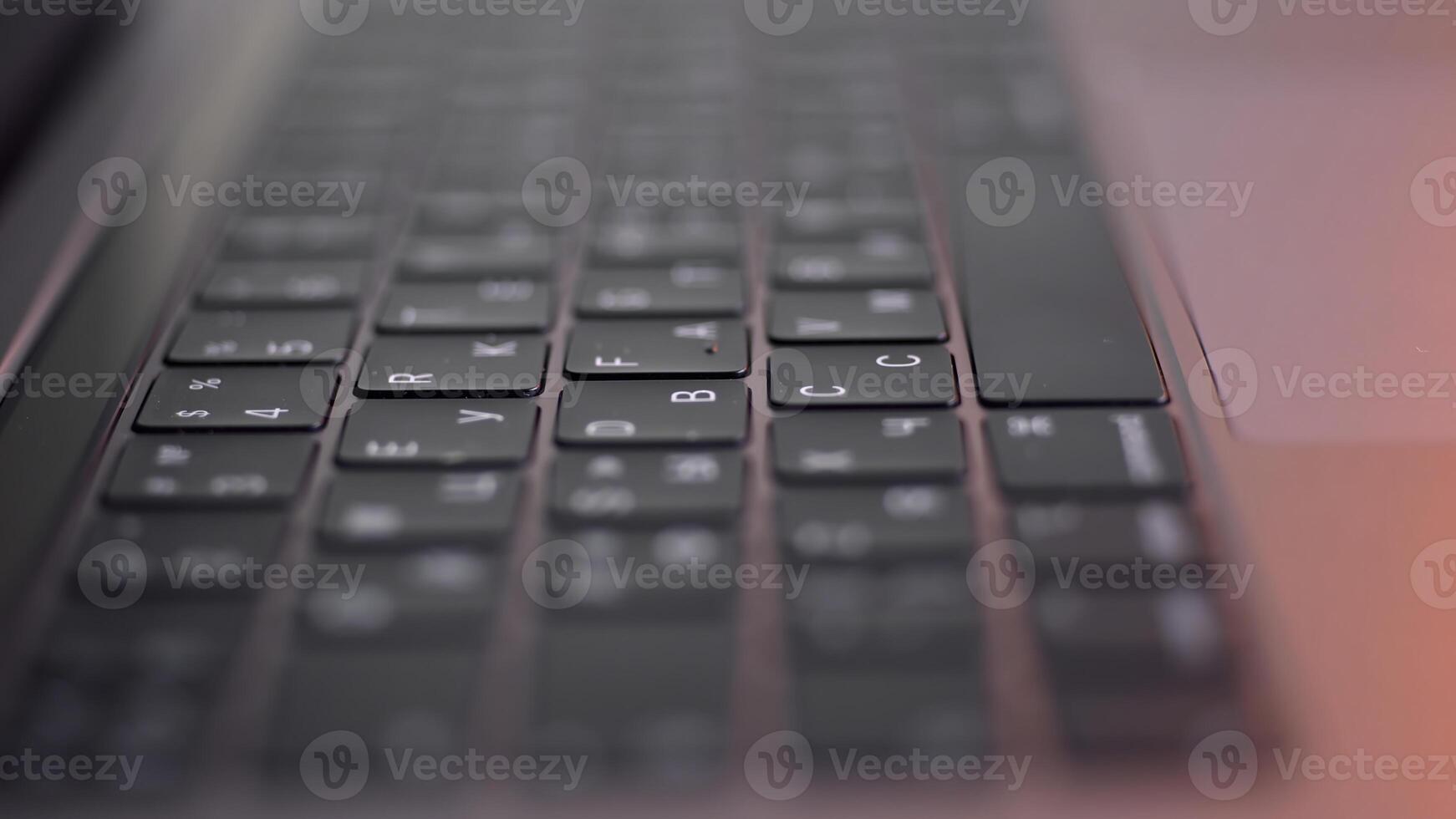 Perspective of a modern computer or laptop black keyboard on pink background, close up view. Action. New keypad with black buttons and white symbols on them, modern technologies concept. photo