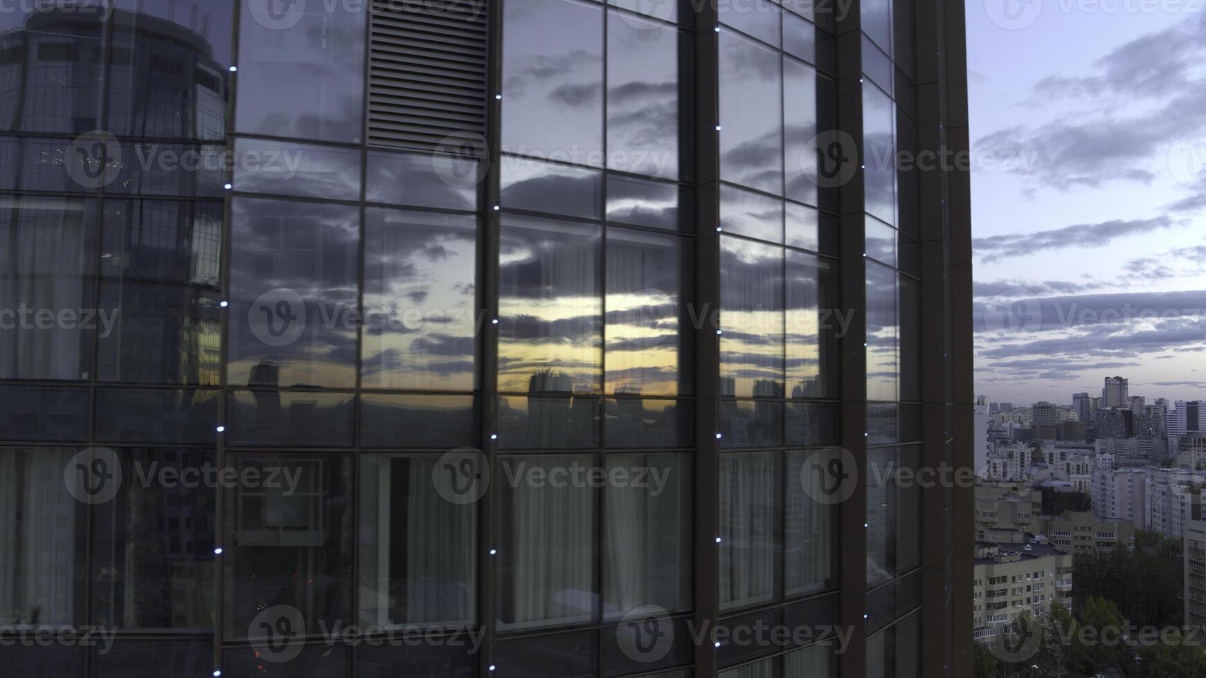 Top view of sunset reflection in windows of business high-rise. Stock footage. Modern skyscraper with glass windows and reflection. Reflection of city and sunset in windows of business building photo