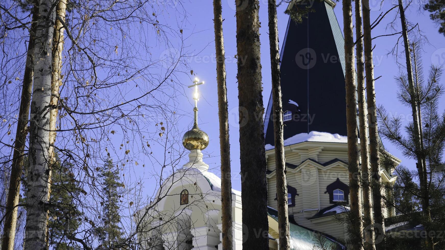 Winter landscape with snow-covered trees against the background of a Christian church after a snowfall. Frosty sunny day photo