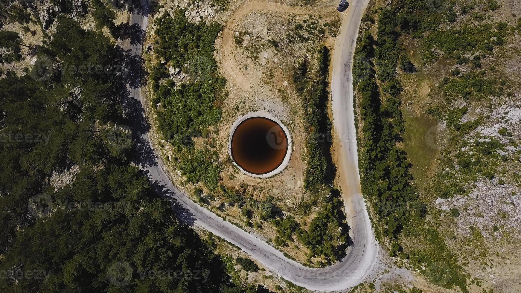 Top view of Sinkhole. Clip. Incredible natural phenomenon in form of sinkhole with brown water in field. Karst sinkhole with water near highway in field photo