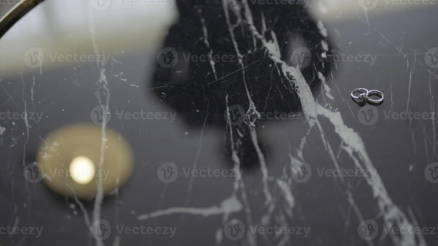 Reflection of groom in table with rings. Action. Close-up of marble table reflects gathering groom. Table with wedding rings and reflection of groom preparing photo