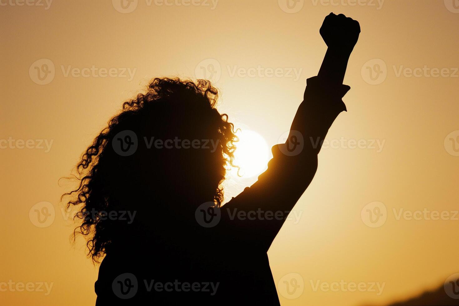 AI generated silhouette of a woman with flowing hair with her fist raised up in the sunset sky, girl power photo