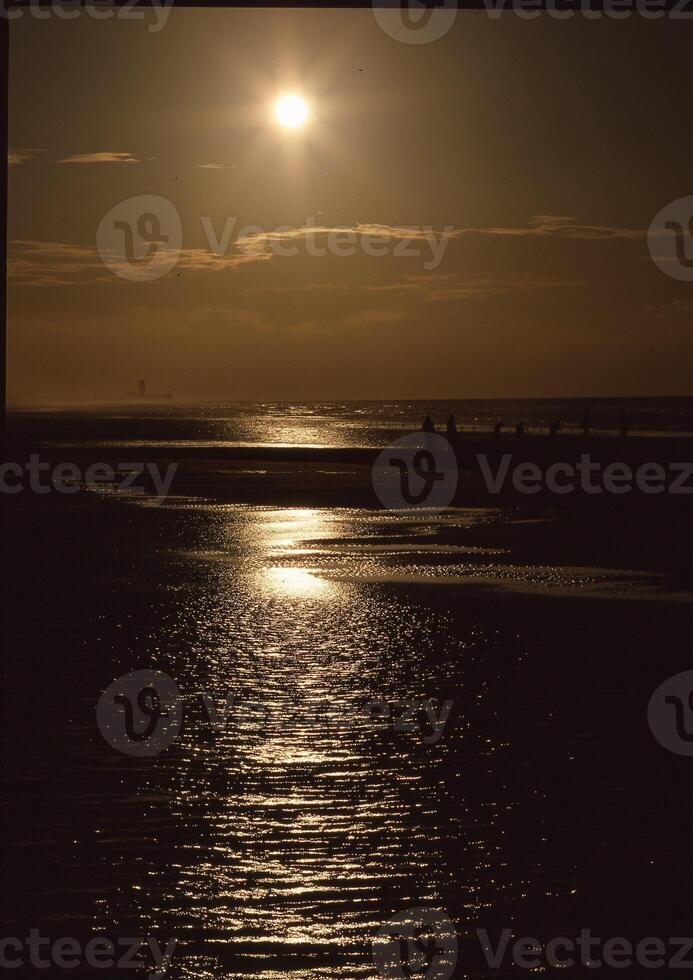 a sunset over the ocean with a boat in the water photo