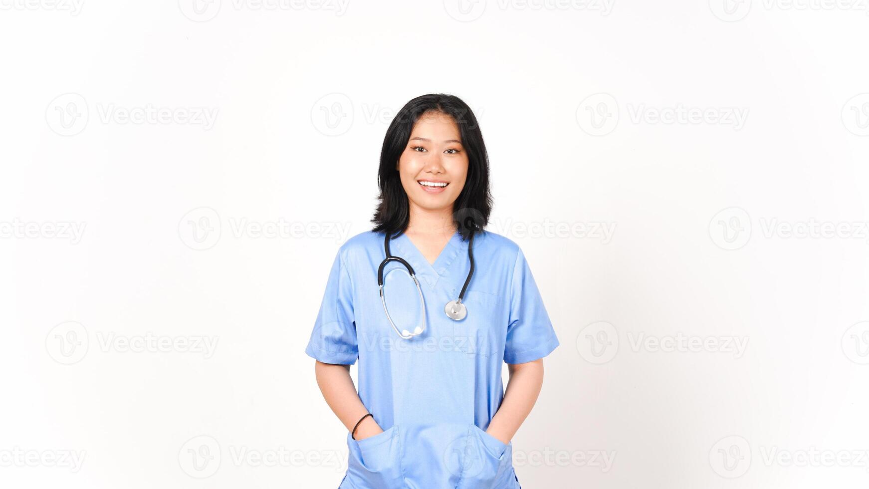 joven asiático hembra médico manos en bolsillo mirando cámara y sonrisa aislado en blanco antecedentes foto