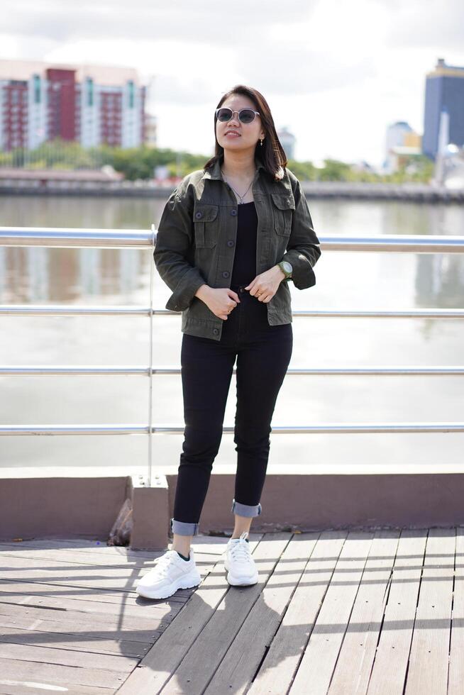 Young Beautiful Asian Woman Wearing Jacket And Black Jeans Posing Outdoors photo