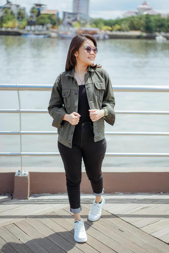 Young Beautiful Asian Woman Wearing Jacket And Black Jeans Posing Outdoors photo