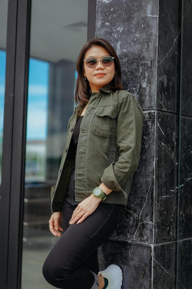 Young Beautiful Asian Woman Wearing Jacket And Black Jeans Posing Outdoors photo