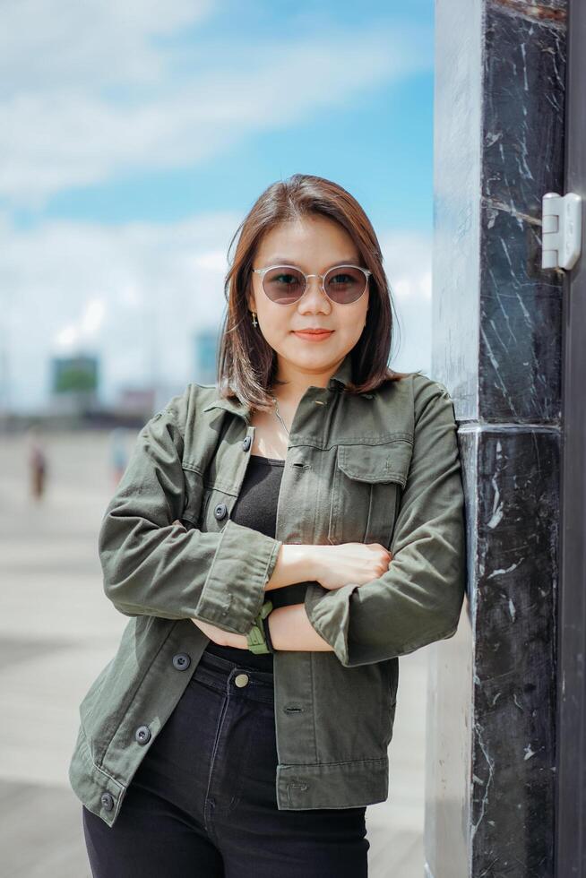 Young Beautiful Asian Woman Wearing Jacket And Black Jeans Posing Outdoors photo