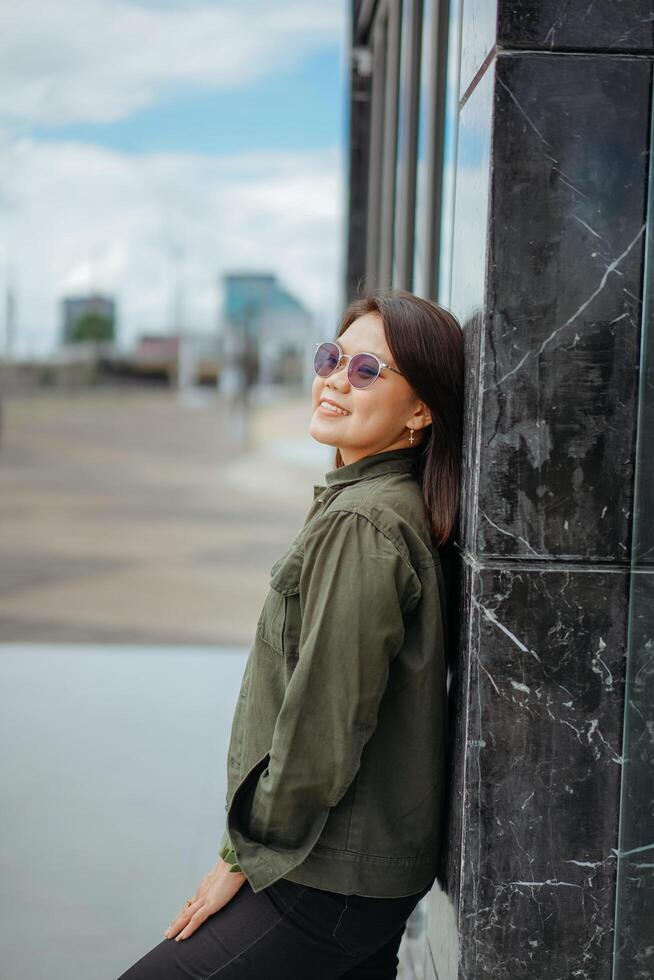 Young Beautiful Asian Woman Wearing Jacket And Black Jeans Posing Outdoors photo