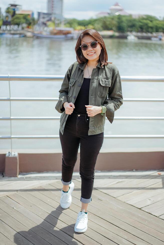 Young Beautiful Asian Woman Wearing Jacket And Black Jeans Posing Outdoors photo