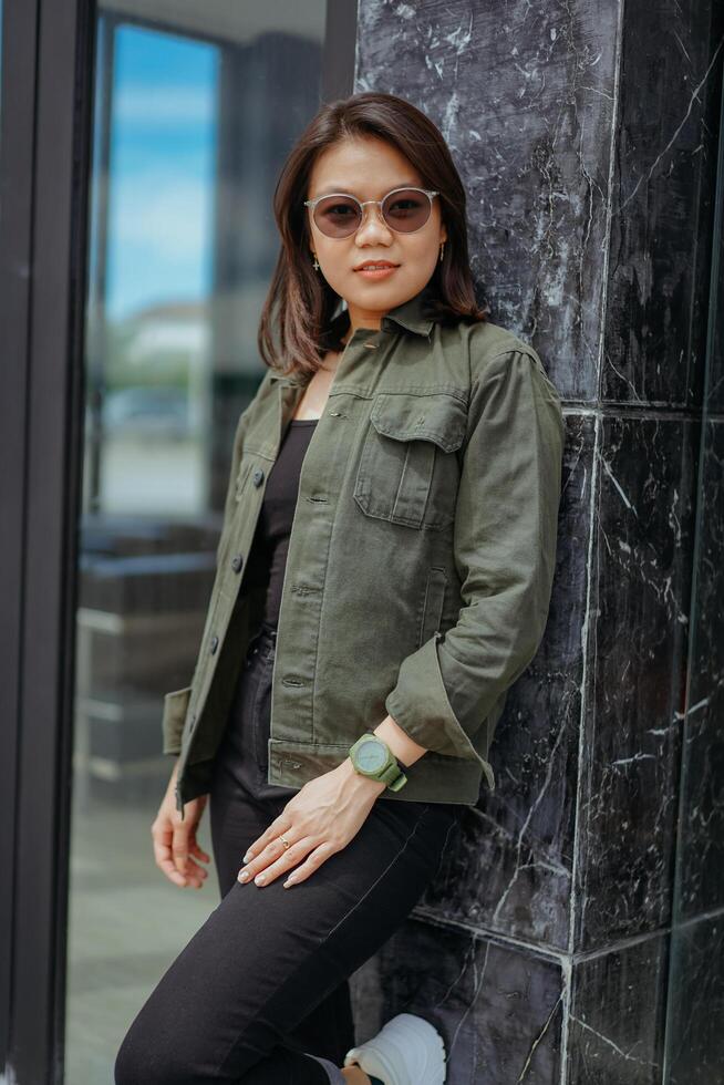 Young Beautiful Asian Woman Wearing Jacket And Black Jeans Posing Outdoors photo