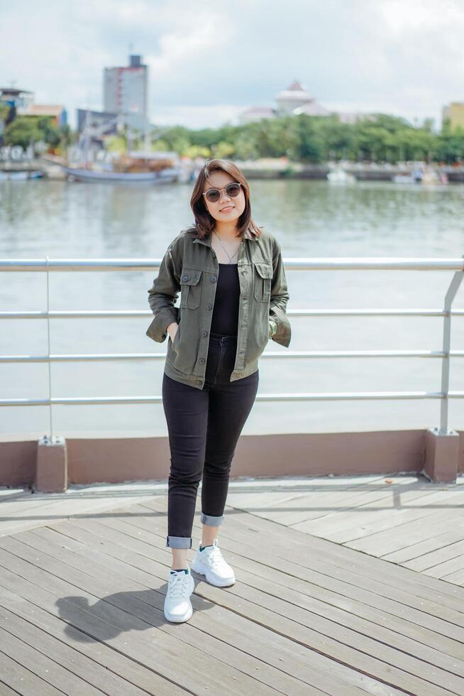 Young Beautiful Asian Woman Wearing Jacket And Black Jeans Posing Outdoors photo
