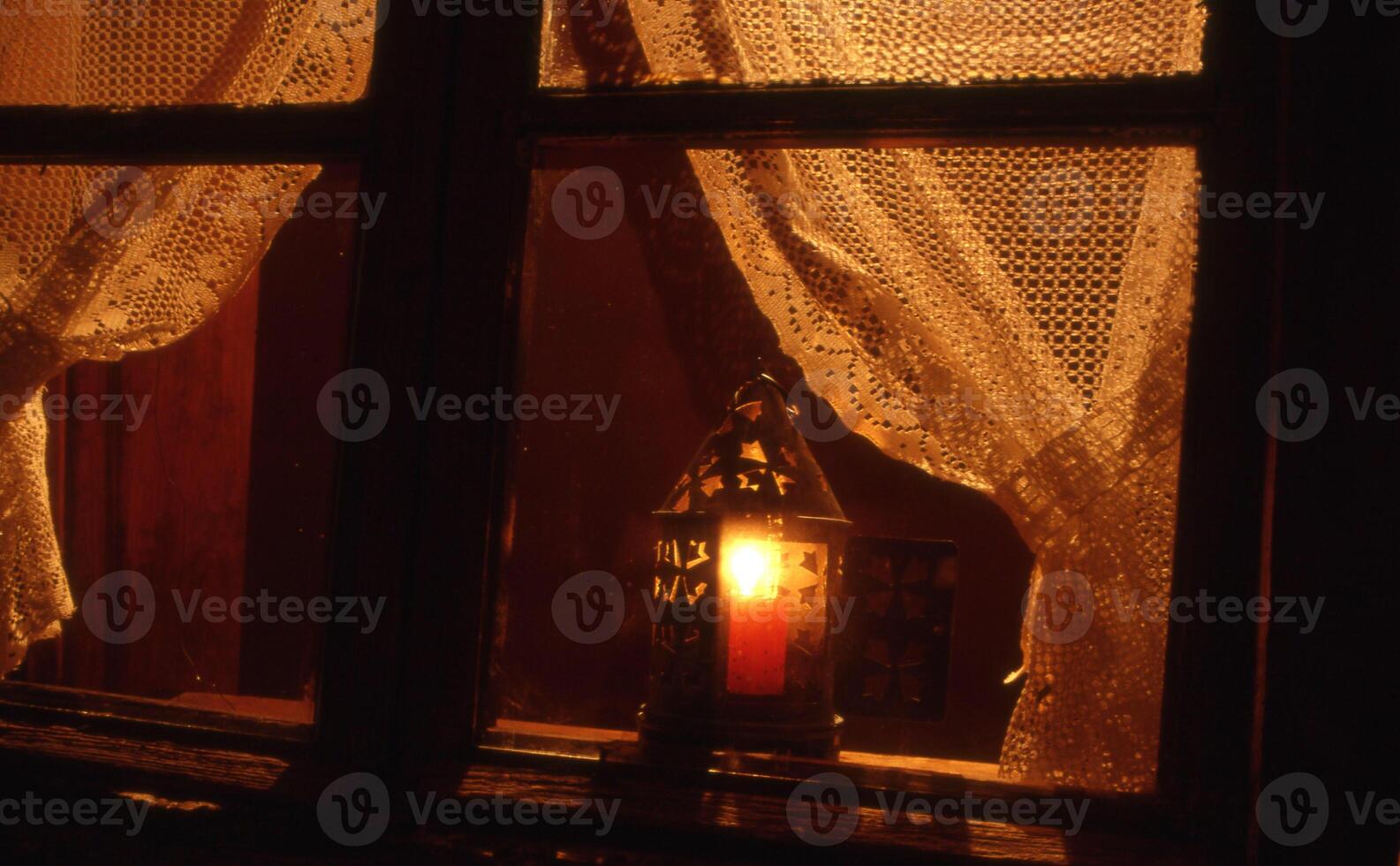 a candle lit by a lantern in a window photo