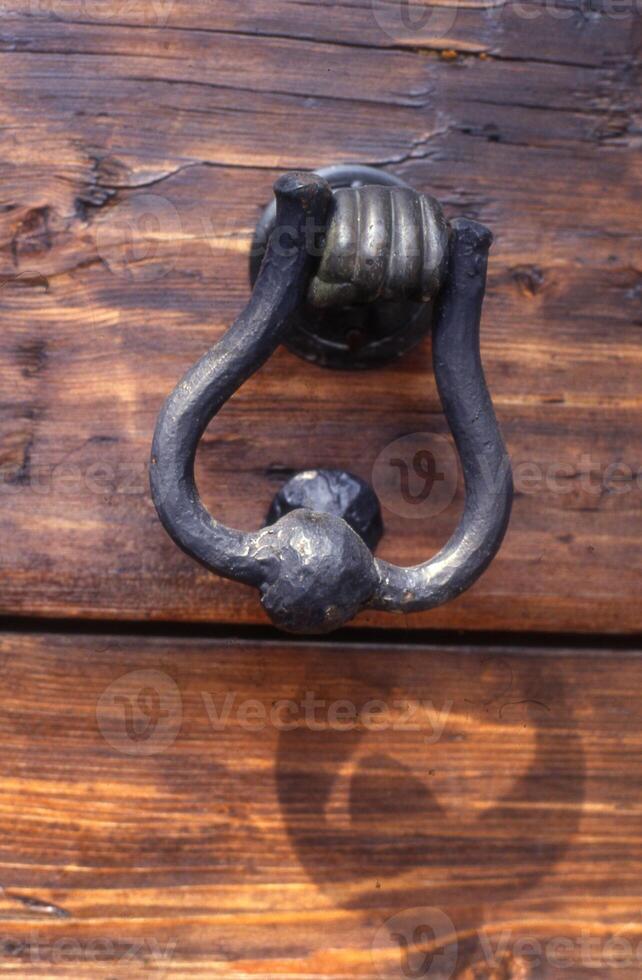 a close up of a metal door knocker on a wooden door photo