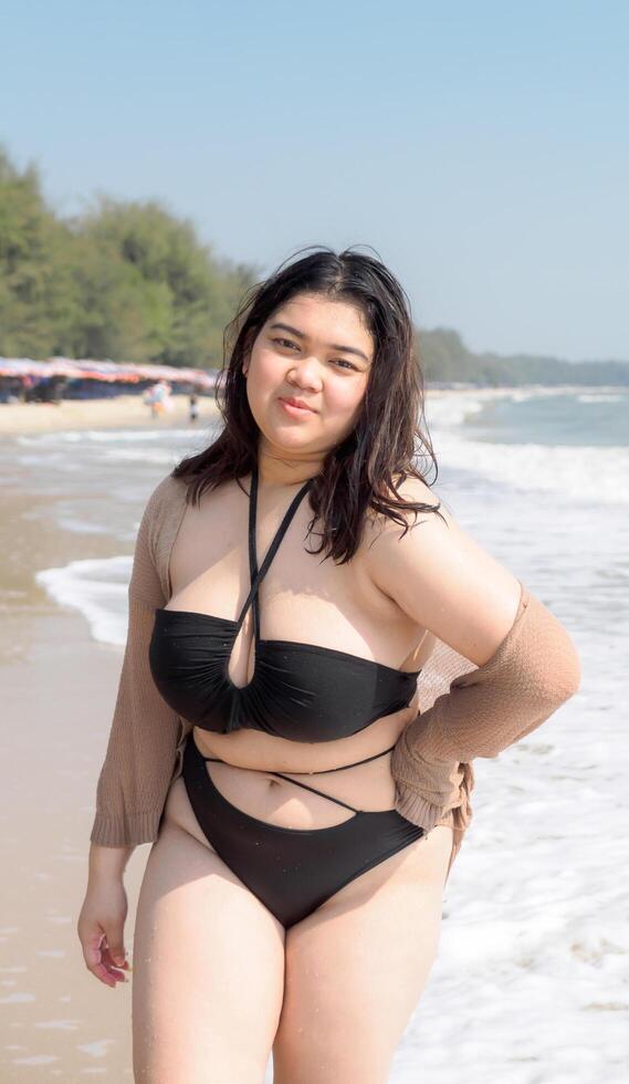 Portrait young asian woman fat chubby cute beautiful smile happy fun bikini swimwear body sexy front view tropical sea beach white sand clean and bluesky calm nature ocean wave water travel on holiday photo