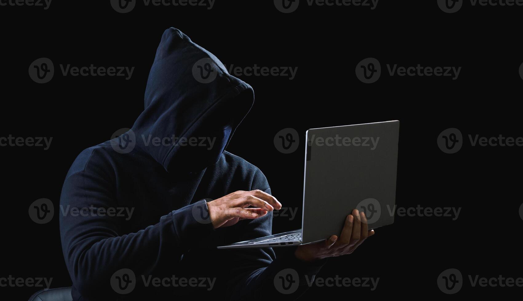 Portrait hacker spy man one person in black hoodie sitting on table looking computer laptop used login password attack security to data digital internet network system night dark background copy space photo