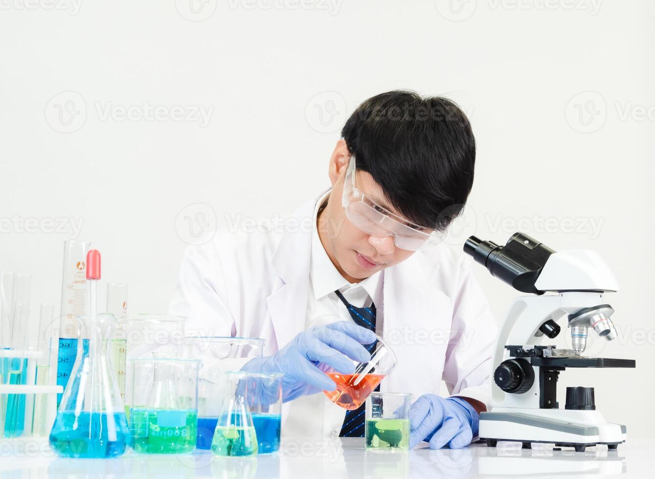 Portrait asian man student scientist Wearing a doctor gown in the lab looking hand at chemist. caused by mixing reagents in scientific research laboratories with test tubes and microscope on the table photo