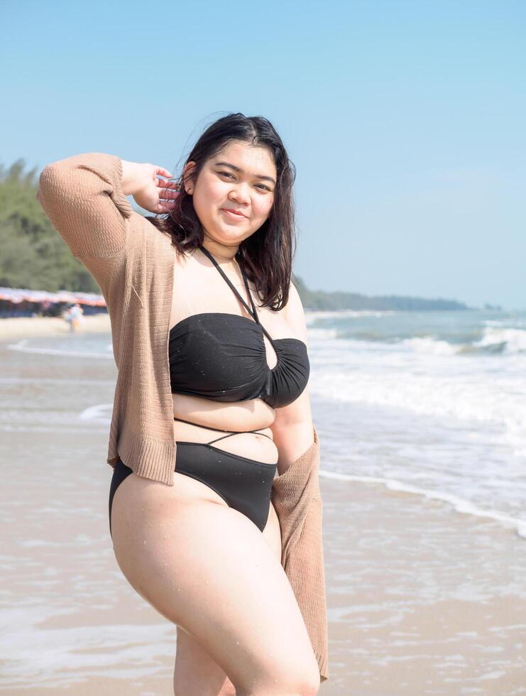 Portrait young asian woman fat chubby cute beautiful smile happy fun bikini swimwear body sexy front view tropical sea beach white sand clean and bluesky calm nature ocean wave water travel on holiday photo