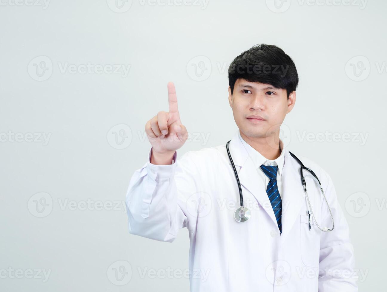 Asian man student scientist or doctor one person, wearing a white gown, standing, looking and smiling, white background with a stethoscope auscultating the heart around his neck. photo