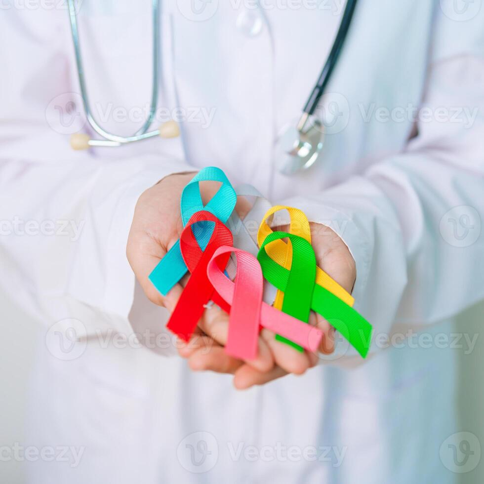 World cancer day, February 4. Doctor hold colorful ribbons, blue, yellow, red, green, white, pink and grey for supporting people living and illness. Health, Medical, awareness and Insurance concept photo