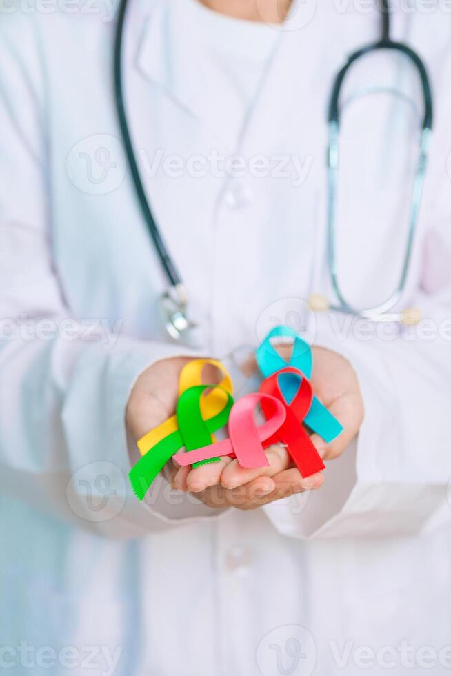 World cancer day, February 4. Doctor hold colorful ribbons, blue, yellow, red, green, white, pink and grey for supporting people living and illness. Health, Medical, awareness and Insurance concept photo