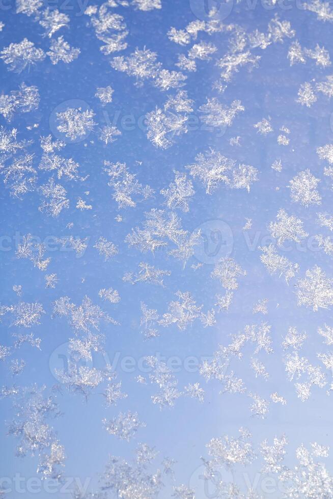 Abstract winter background. Frost on a frozen window against the blue sky. photo