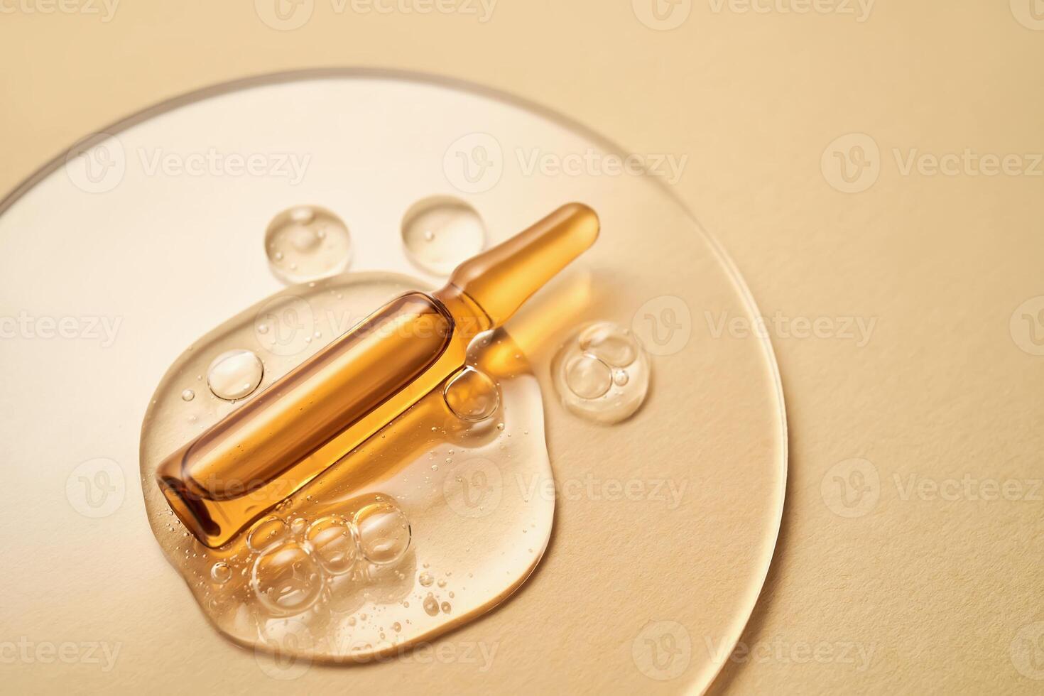 Ampoule in a drop of cosmetic gel on a beige background. photo