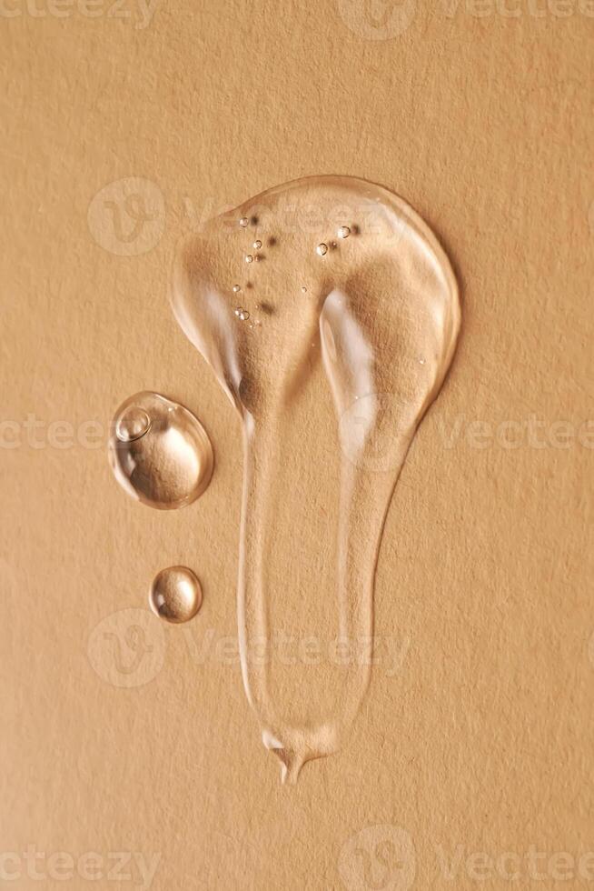 A drop of transparent cosmetic gel on a beige background. photo