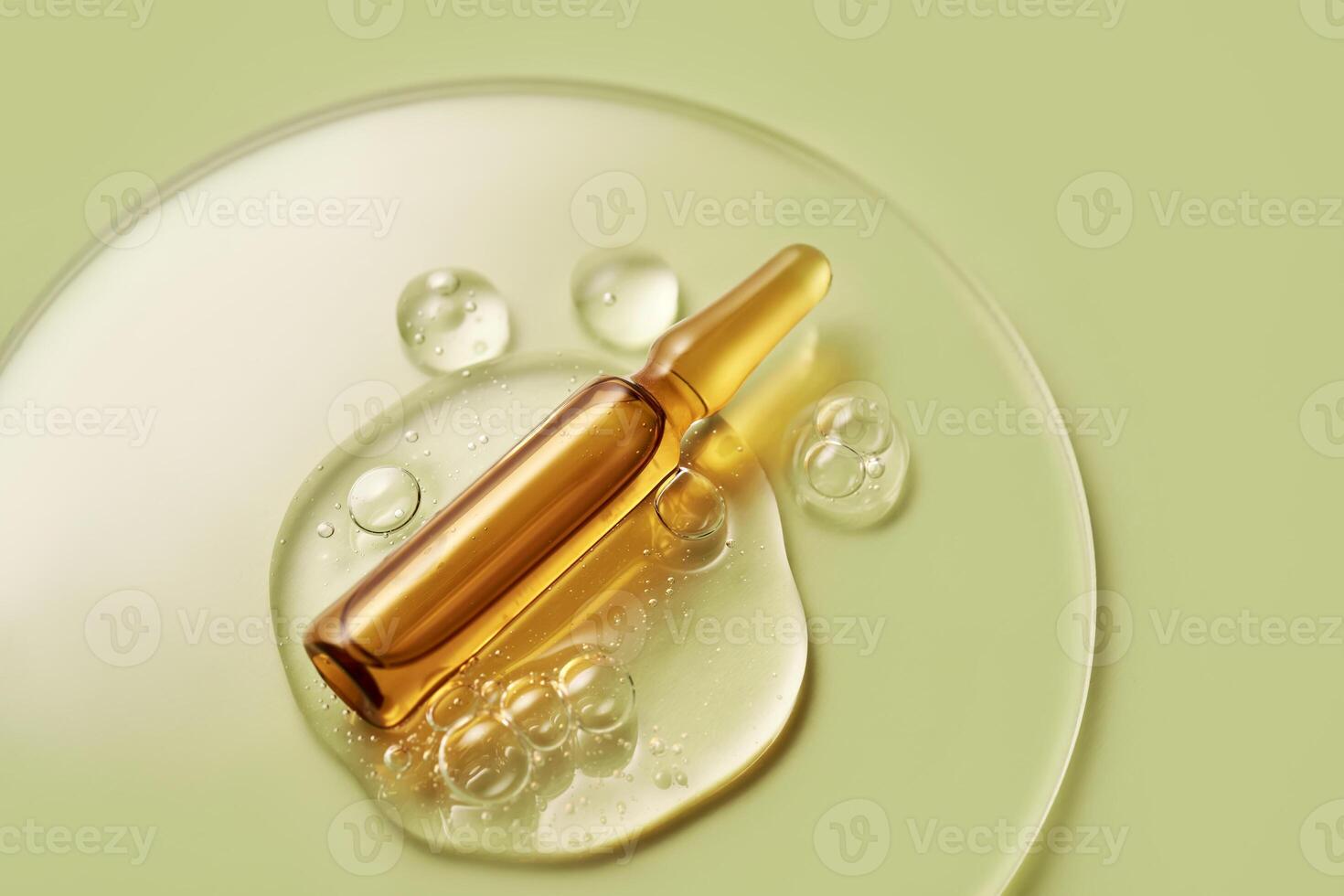 Ampoule in a drop of cosmetic gel on a green background. photo