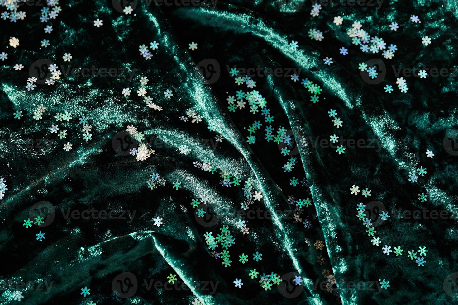 Snowflake shaped confetti on green velvet. Christmas background. photo