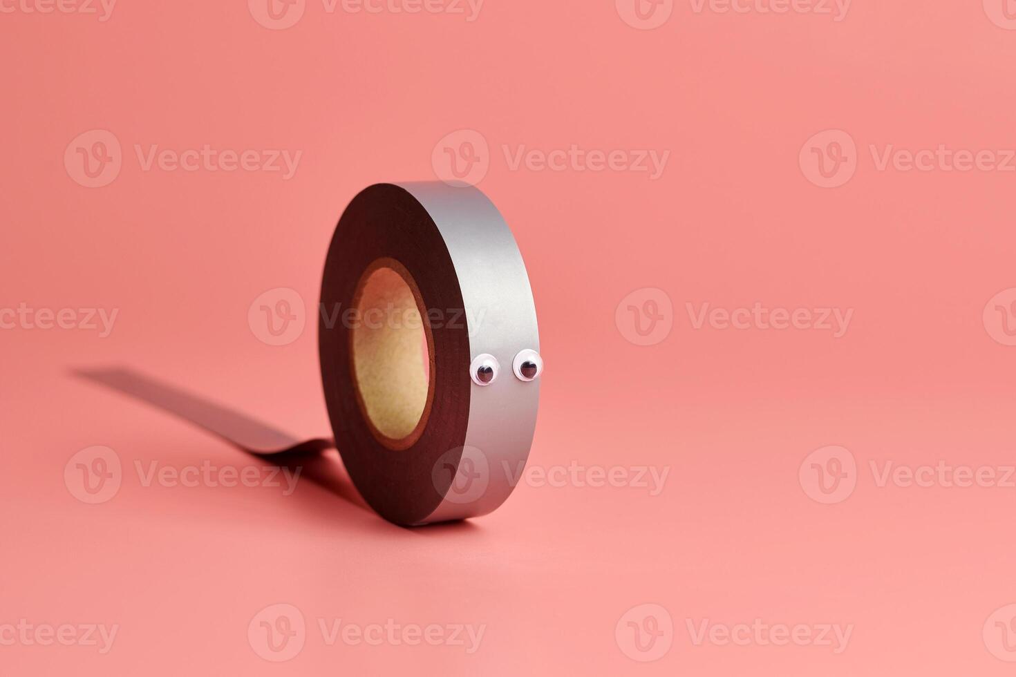 Electrical tape roll, copy space. Cute eyes, minor repairs in house concept. Minimal pink background. photo