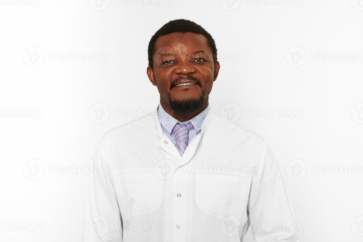 Happy black doctor man with small beard in white coat bright shirt isolated on white background photo