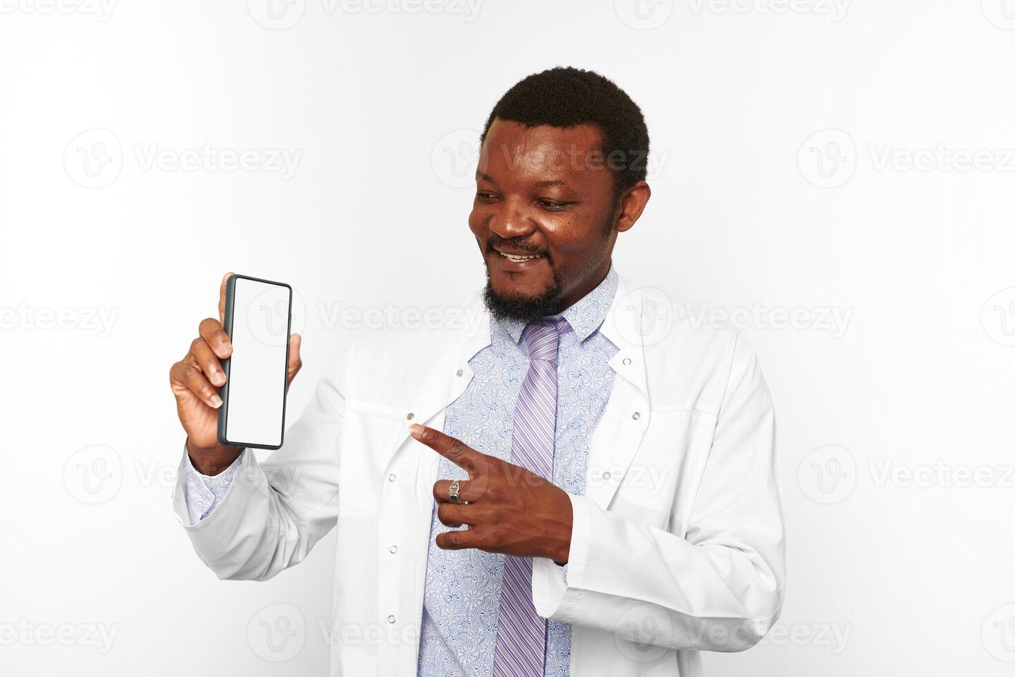 Smiling black doctor man with small beard in white coat holds smartphone blank mockup photo