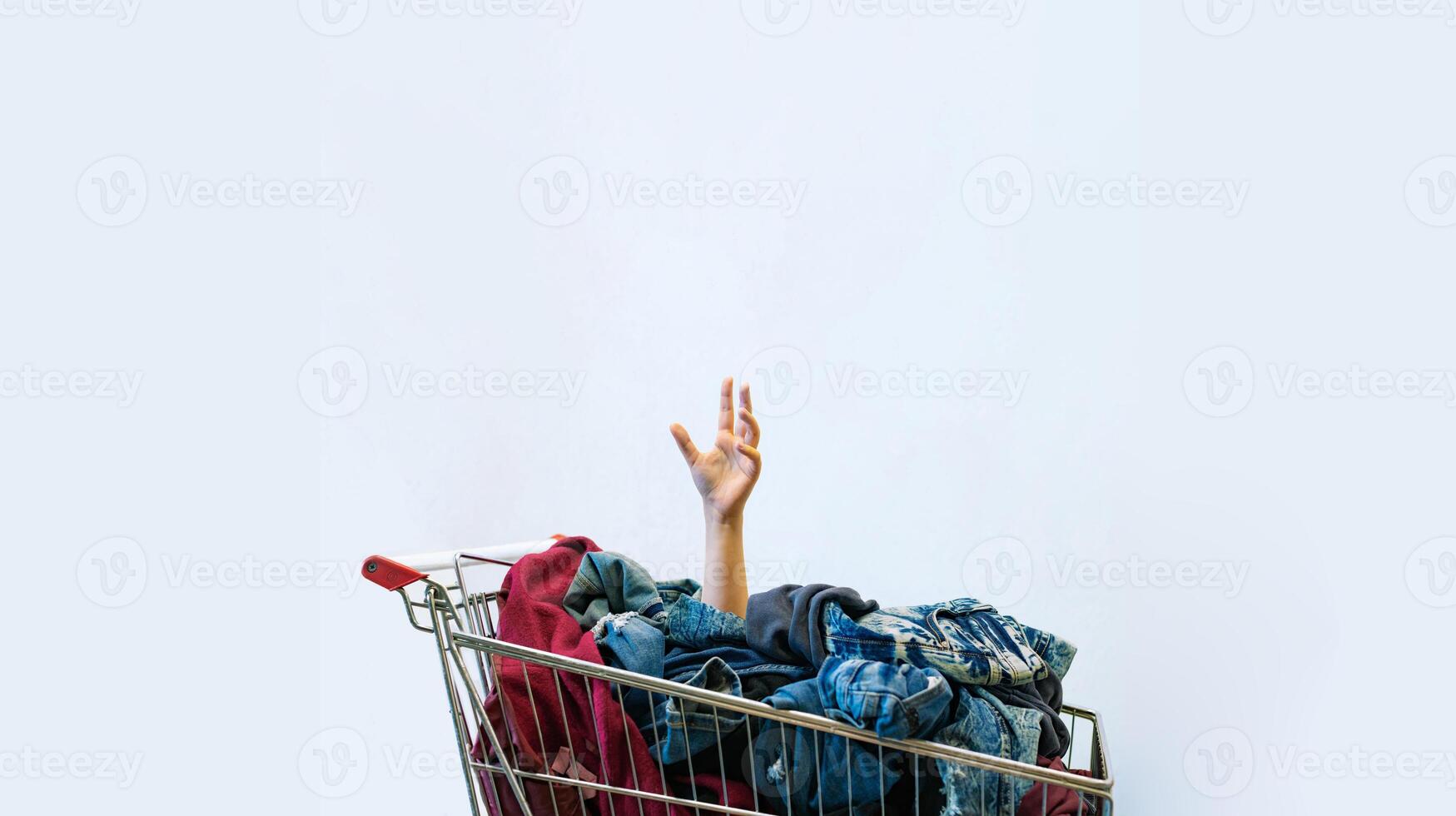 Shopaholic concept. Female hand sticks out of shopping cart photo