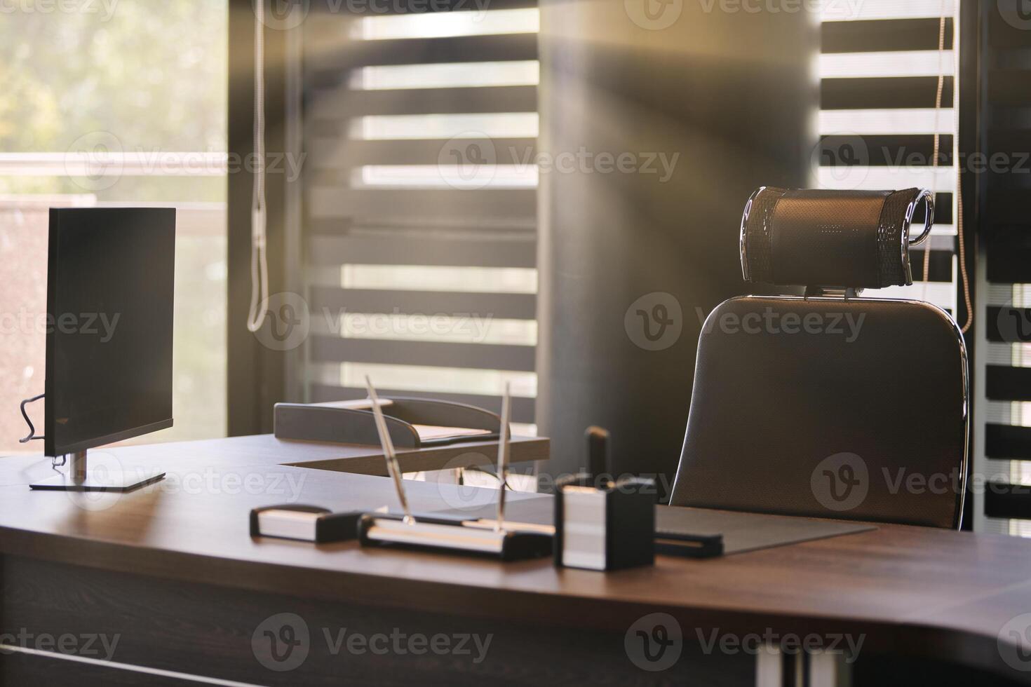 Business office workplace. Sunlight at work place for chief, boss or other employees. Table and comfortable chair. Light through the half open blinds photo