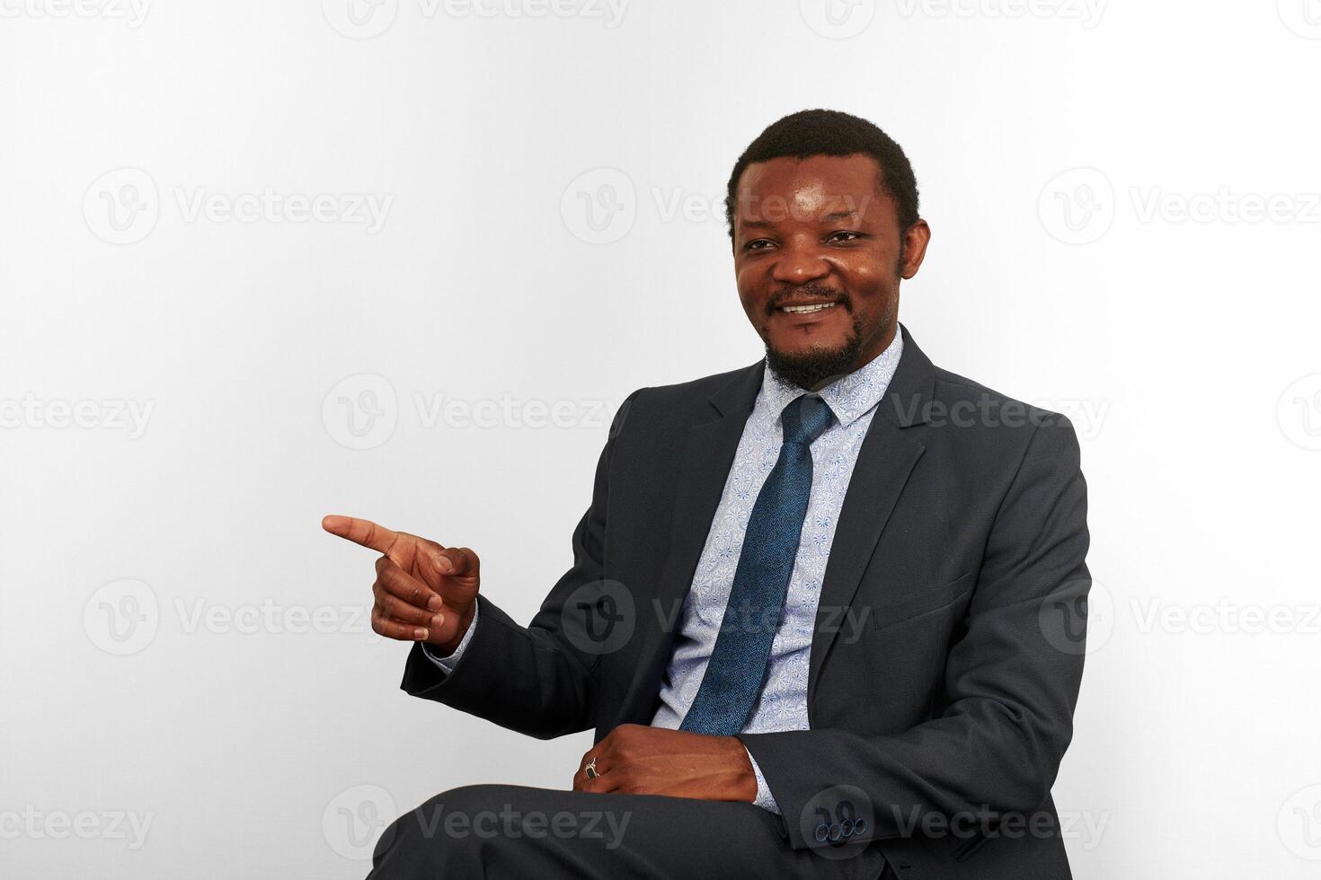 sonriente africano americano negro hombre en negocio traje sentado en silla y señalando dedo, aislado foto